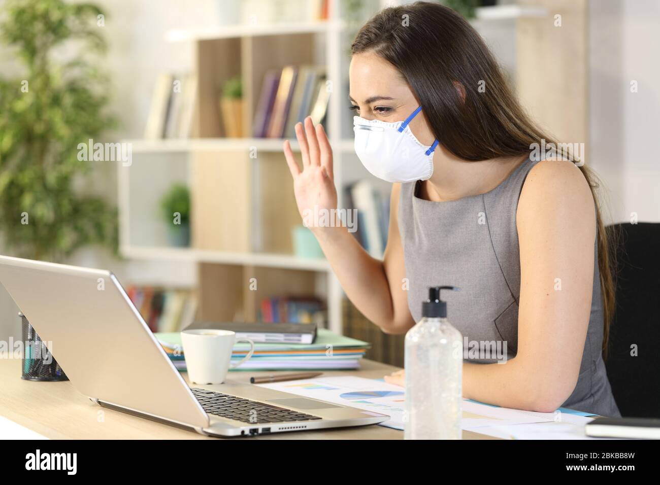 Happy entrepreneur woman greets to laptop webcam on videocall on coronavirus confinement at homeoffice Stock Photo