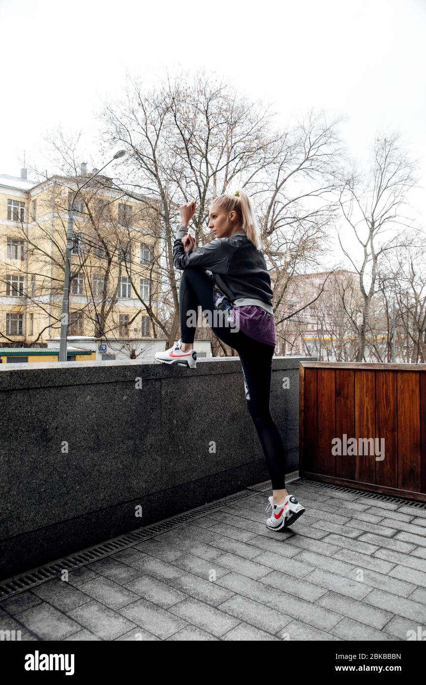 Pretty blonde girl with ponytail is training in sports clothes on the  streets of a city. She is wearing a sporty jacket, leggings and sneakers  Stock Photo - Alamy