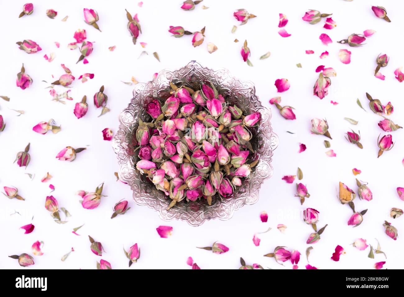 Rose buds. Dry, healthy tea rose buds in silver bowl on white