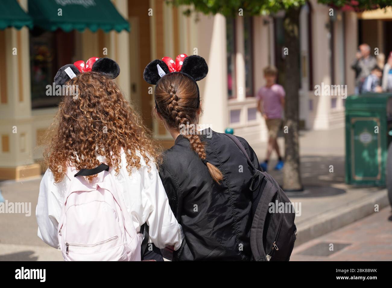 Back of head of two young girls. Staying on the street looking to an attraction in tourist park with other visitors. Paris France, 29. May 2019 Stock Photo