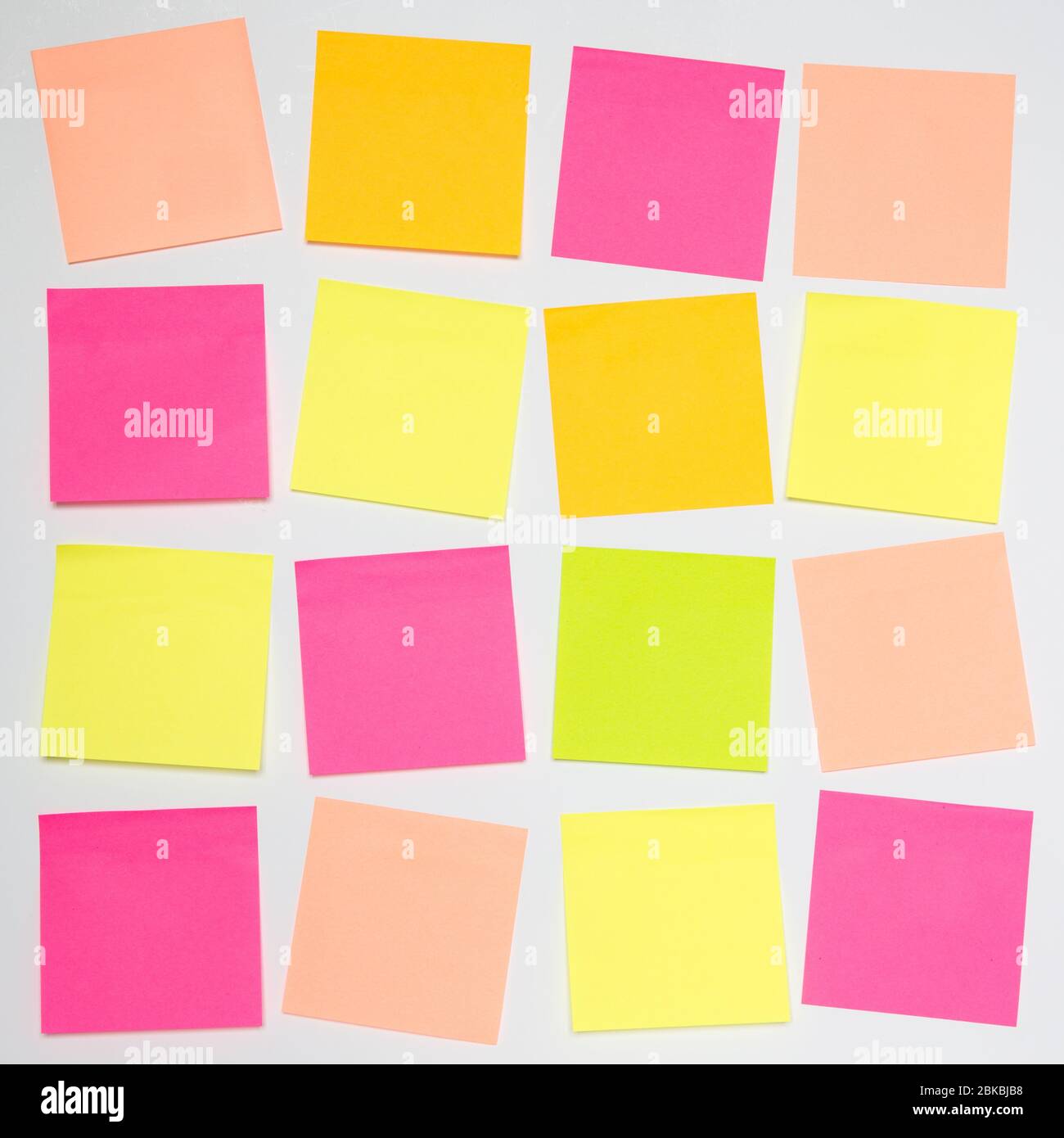 A square grid pattern with lots of blank, colourful sticky notes or adhesive note paper on a white background with copy space Stock Photo