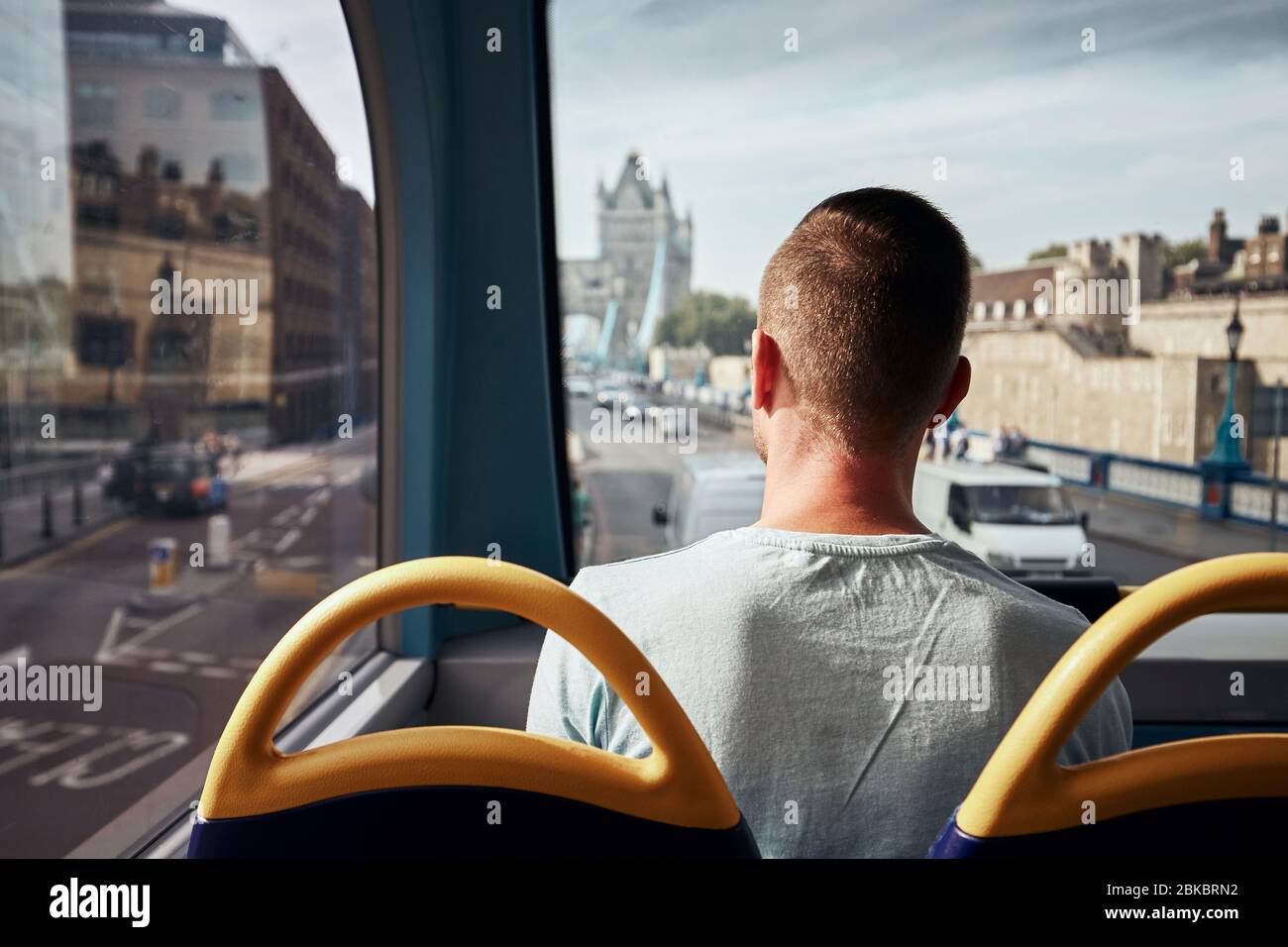 Man traveling by double decker bus against Tower Bridge. City street in London, United Kingdom. Stock Photo