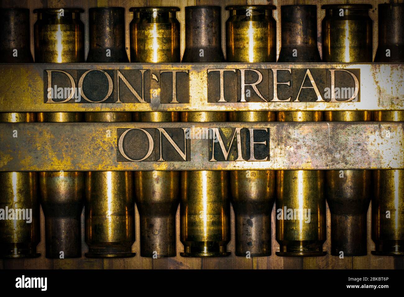 Photo of real authentic typeset letters forming Dont Tread On Me text on vintage textured grunge copper background over layer of 50 caliber bullet cas Stock Photo