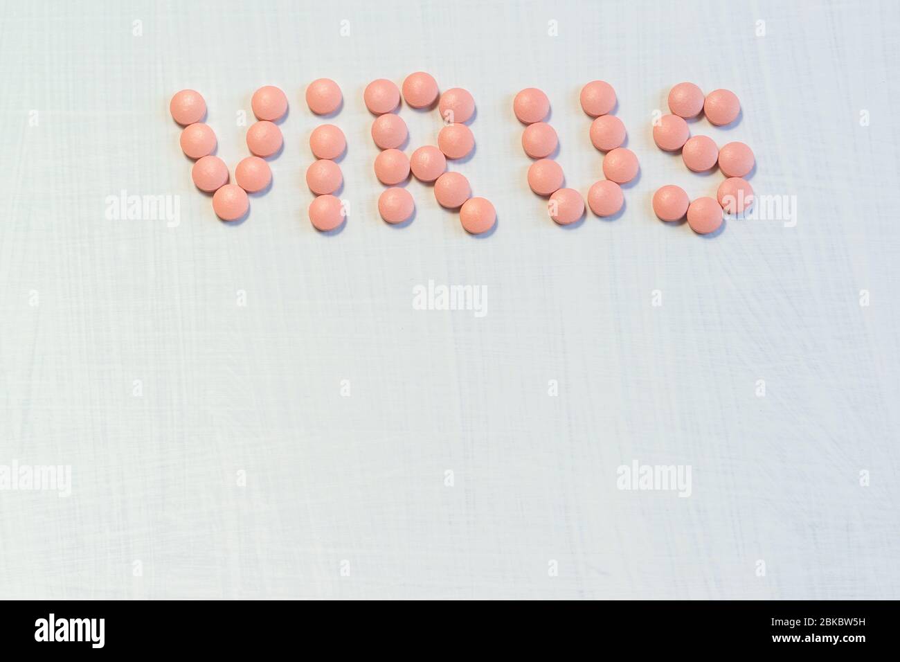 A pandemic of coronavirus pneumonias. On a white background, the inscription virus is laid out in pink tablets. Pharmaceuticals for the treatment of c Stock Photo