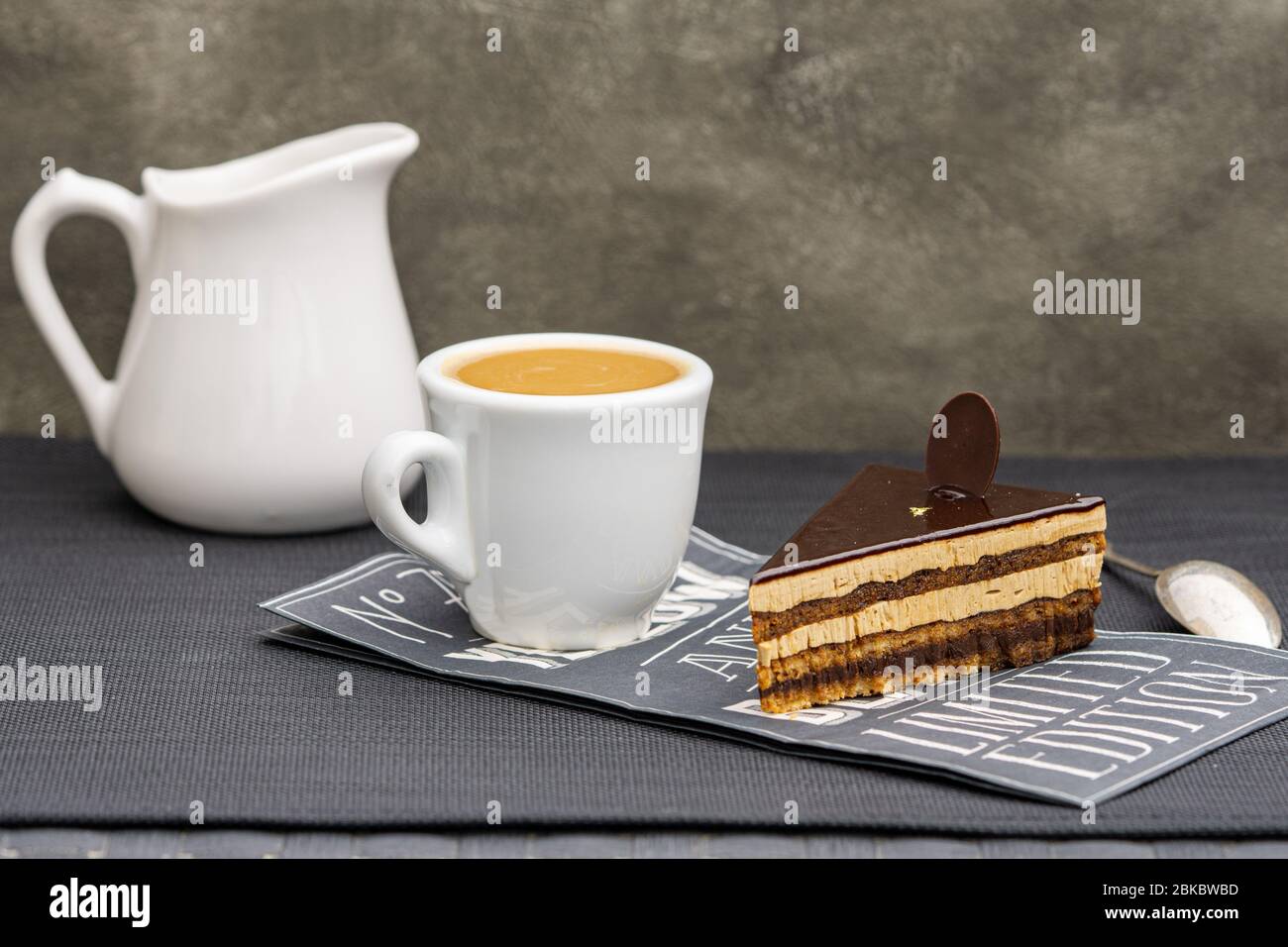 Layered chocolate opera cake with cup of espresso coffee. Copy space. Stock Photo