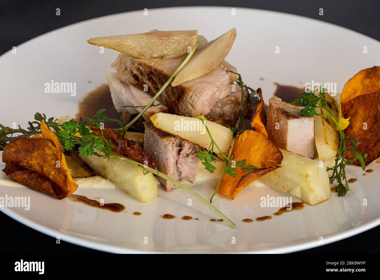 Roasted pork slices with fried potato chips, baked pear Stock Photo Alamy