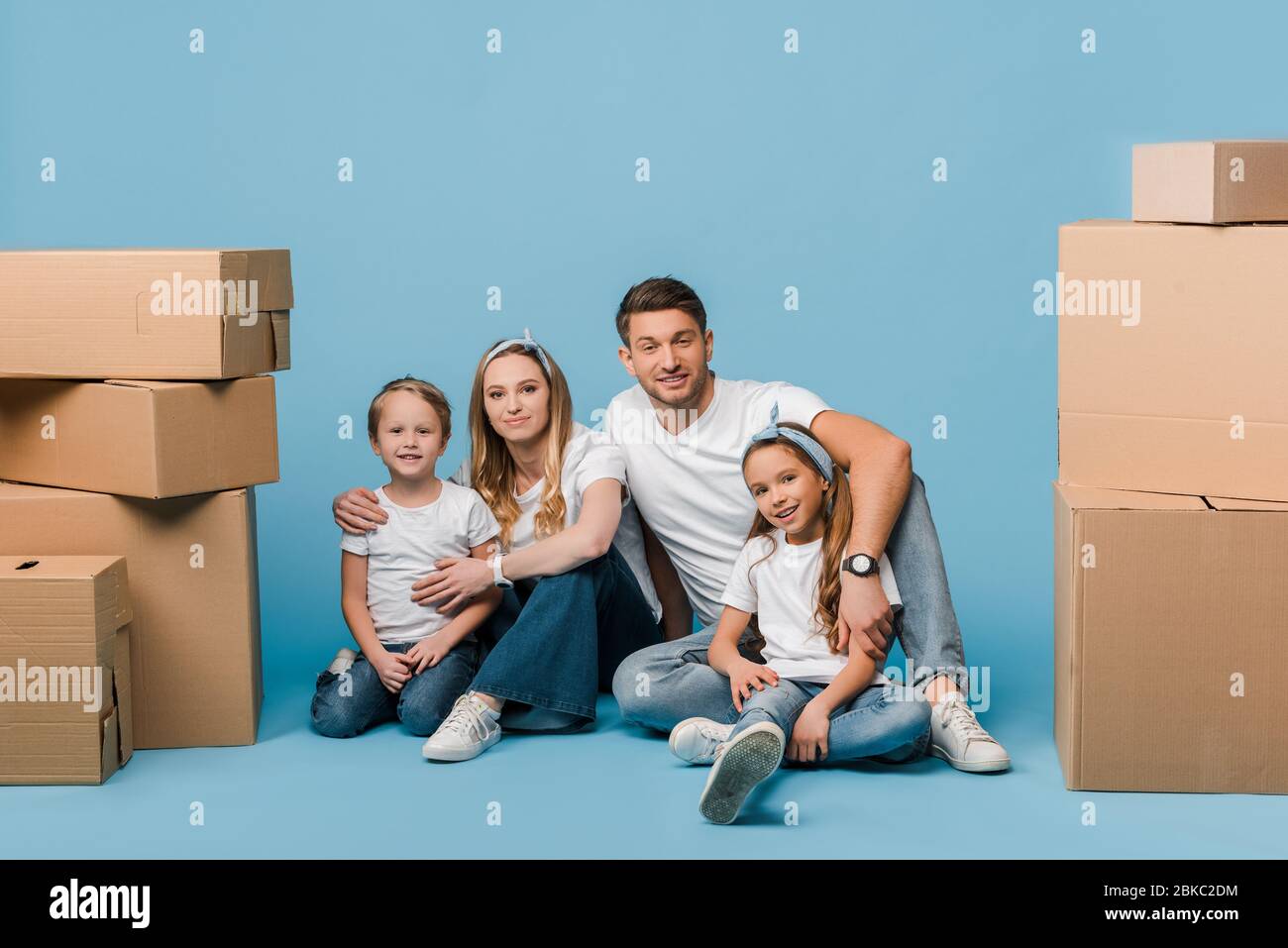 happy parents hugging kids and sitting on blue with cardboard boxes for ...