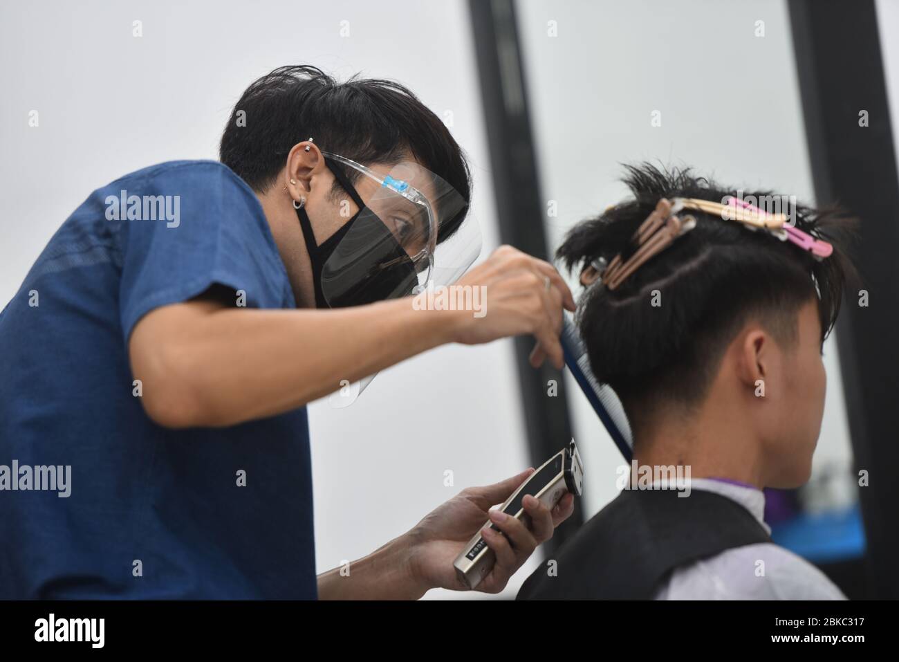A barber of Phoenix Siam salon wearing a face mask as a precaution while  cutting a customer's hair during the partial lift of Coronavirus   a month of Thailand lockdown due to