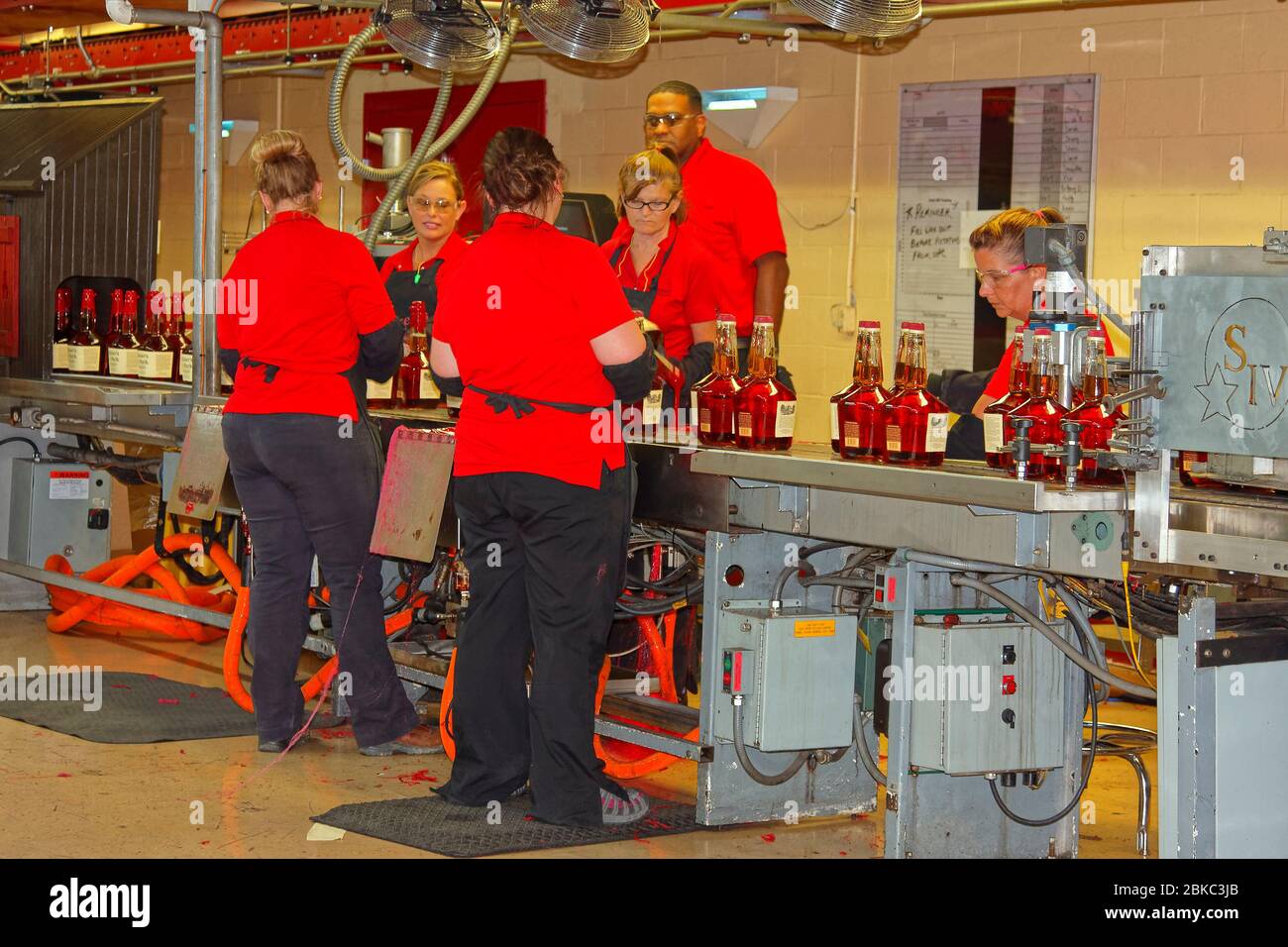 workers hand dipping bottles in red wax, traditional sealing, assembly