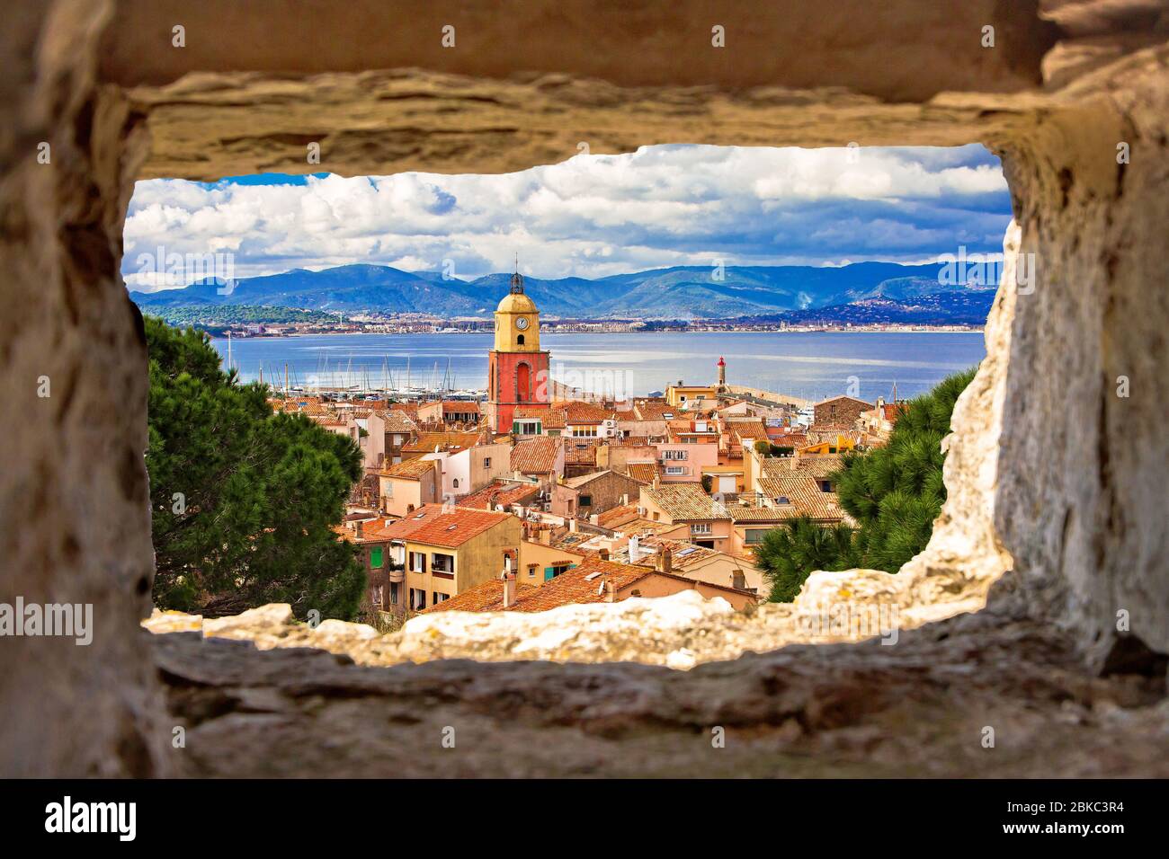 Saint Tropez village church tower and old rooftops view through stone window, famous tourist destination on Cote d Azur, Alpes-Maritimes department in Stock Photo