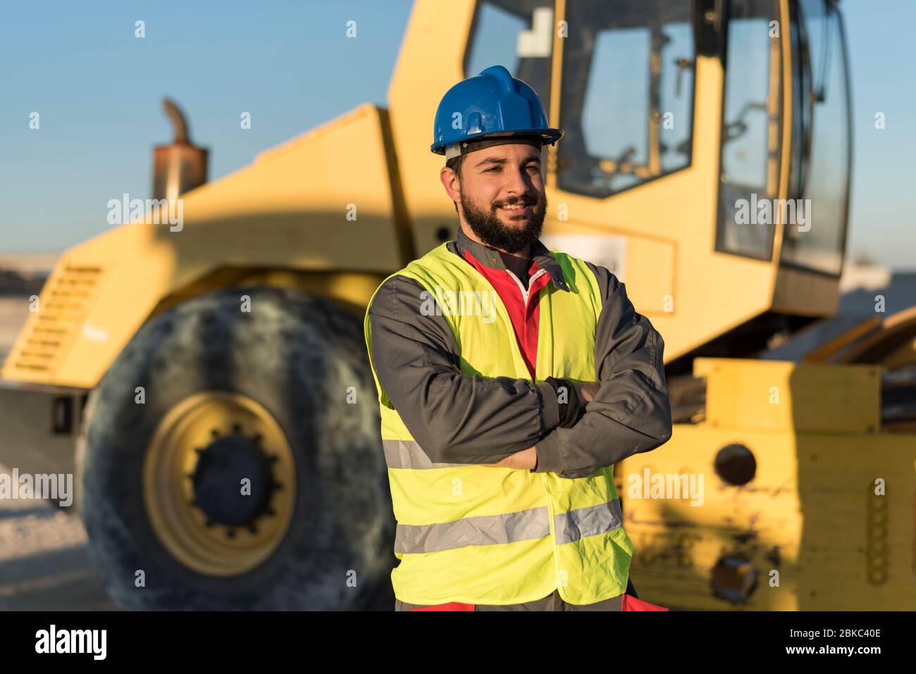 Bearded construction worker posing ner to steam roller machine Stock Photo