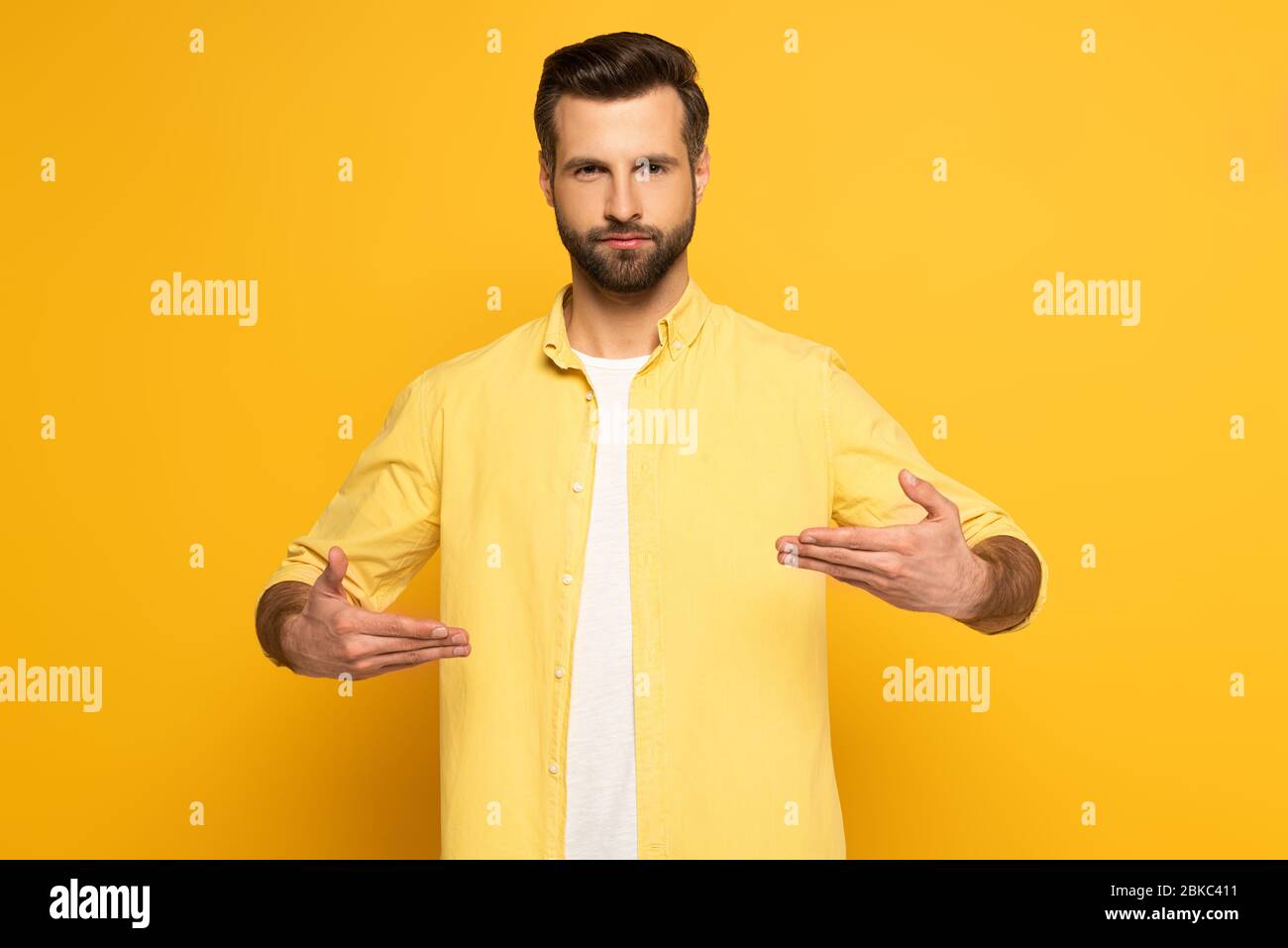 Man looking at camera while using deaf and dumb language on yellow background Stock Photo