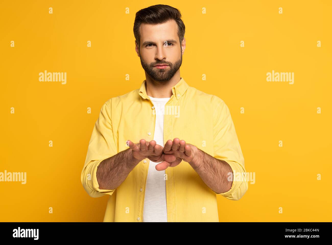 Young man using deaf and dumb language on yellow background Stock Photo