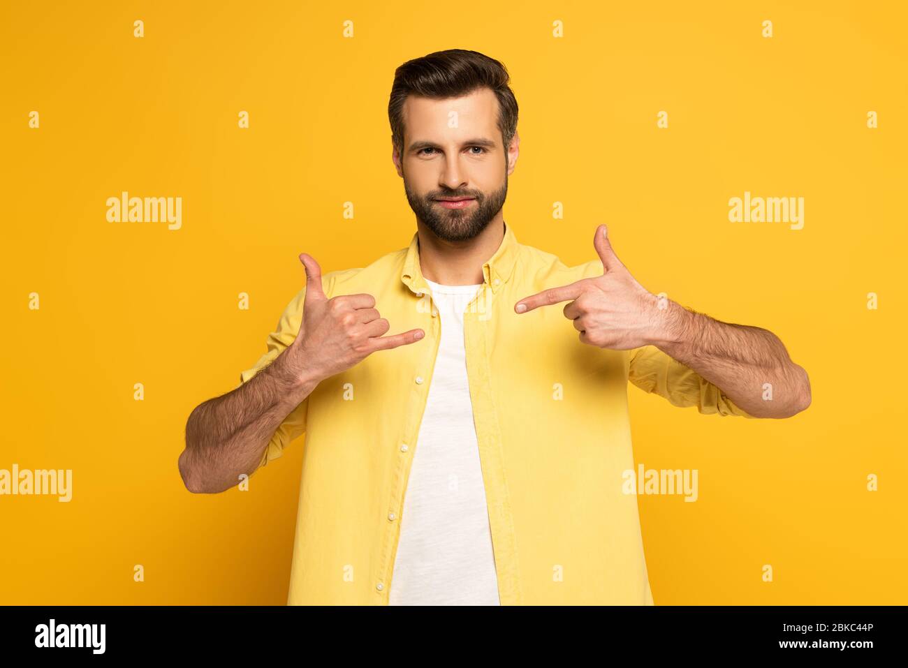 Man looking at camera while using deaf and dumb language on yellow background Stock Photo
