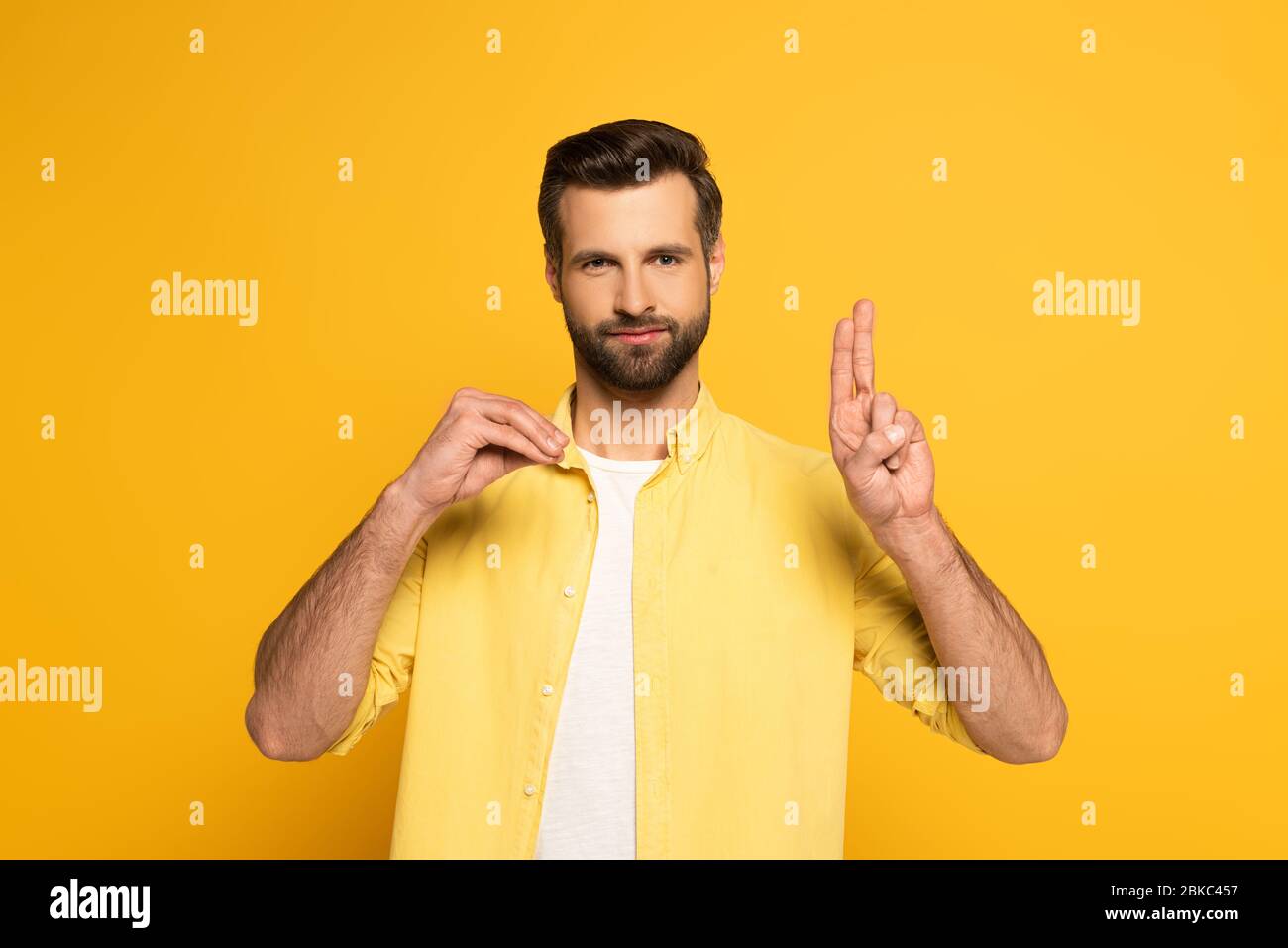 Bearded man showing letters while using deaf and dumb language on yellow background Stock Photo