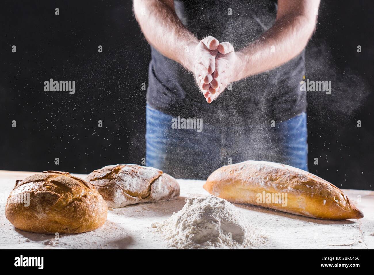 Baker cooking bread. Man slaps flour. Food concept. Stock Photo