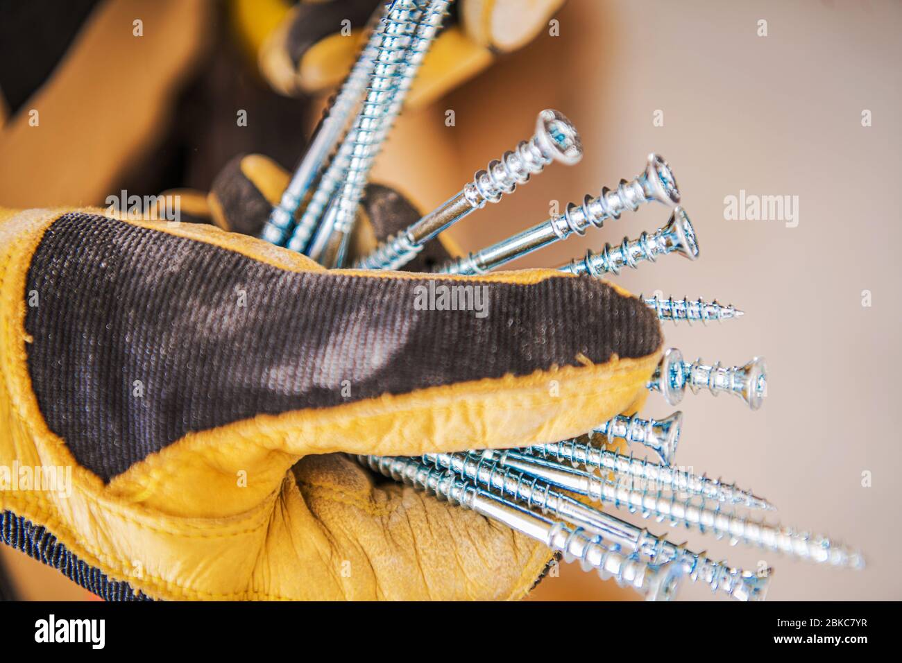 Construction Metal Screws in Worker's Hand. Industrial Theme. Safety Gloves. Stock Photo
