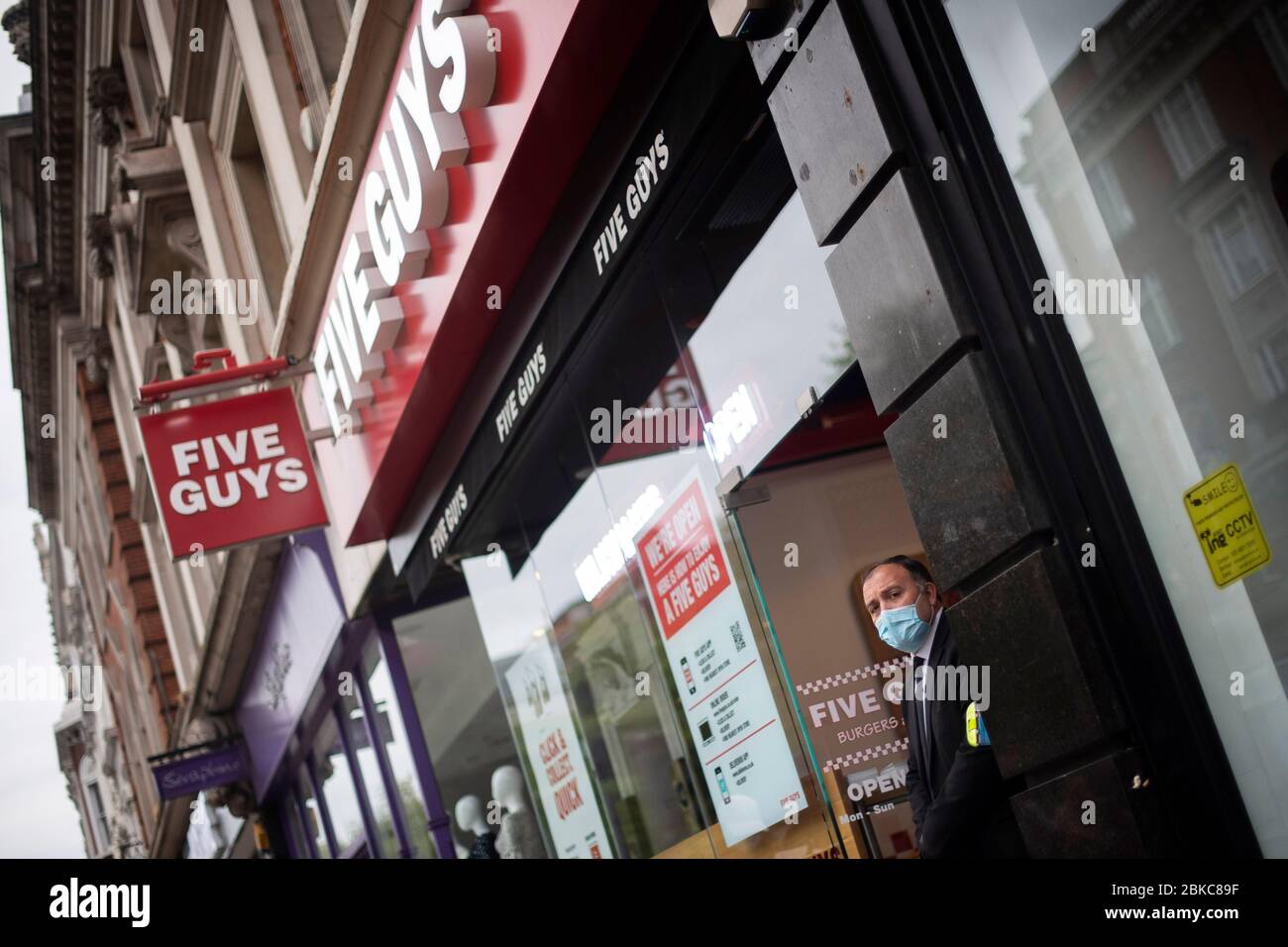 A security man on the door of Five Guys restaurant in Kensington, London, after the burger chain reopened eight of their sites, as the UK continues in lockdown to help curb the spread of the coronavirus. Stock Photo