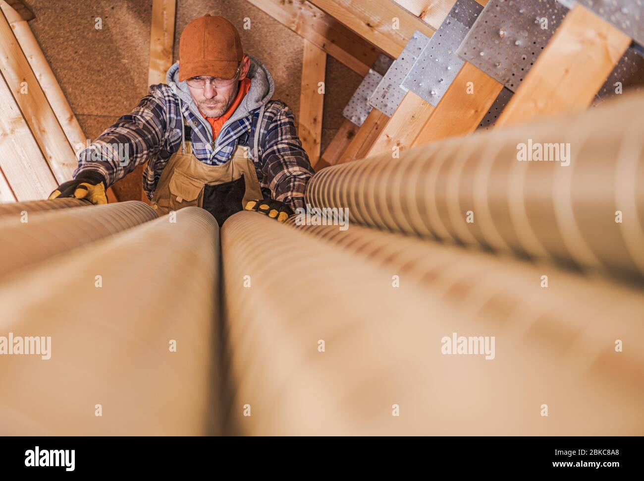 Industrial Theme. Residential Air Ventilation Pipelines Prepared by Caucasian Technician Worker. Home Air Quality. Stock Photo