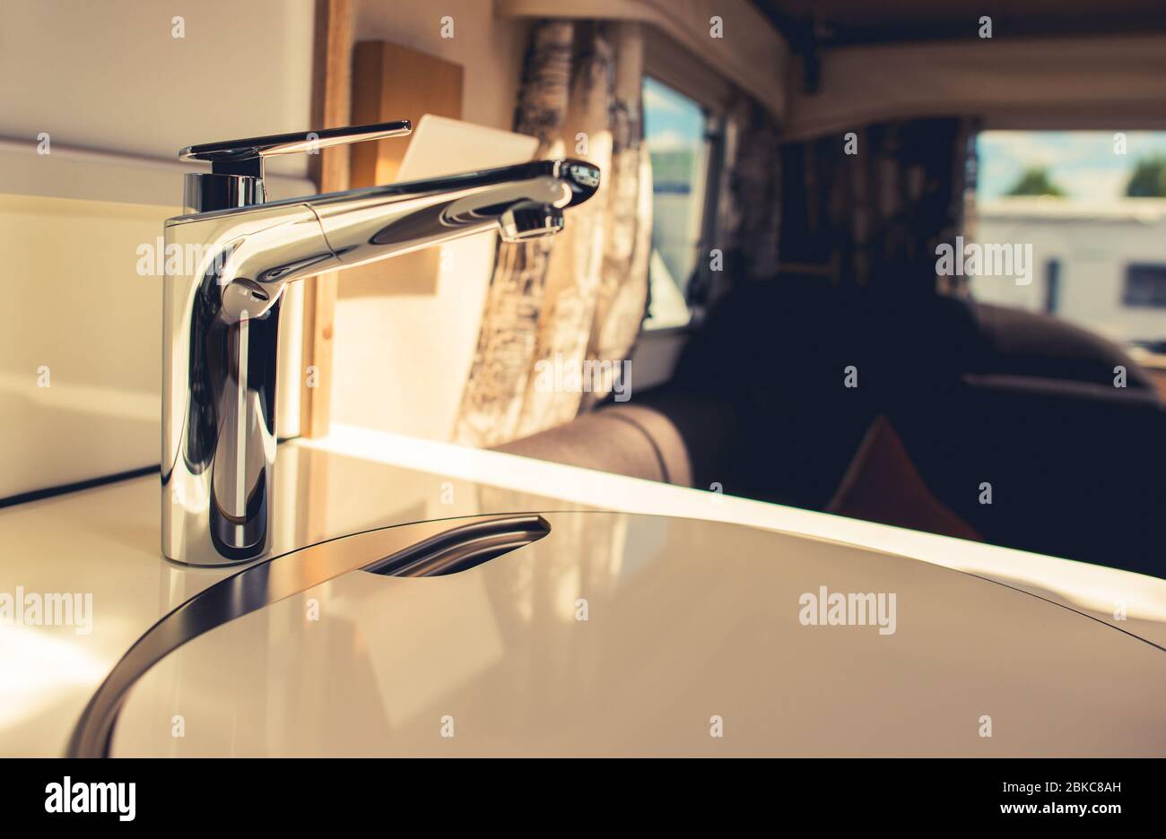 Modern RV Recreation Vehicle Travel Trailer Sink in a Kitchen Area. Cooking on the Road Theme. Stock Photo