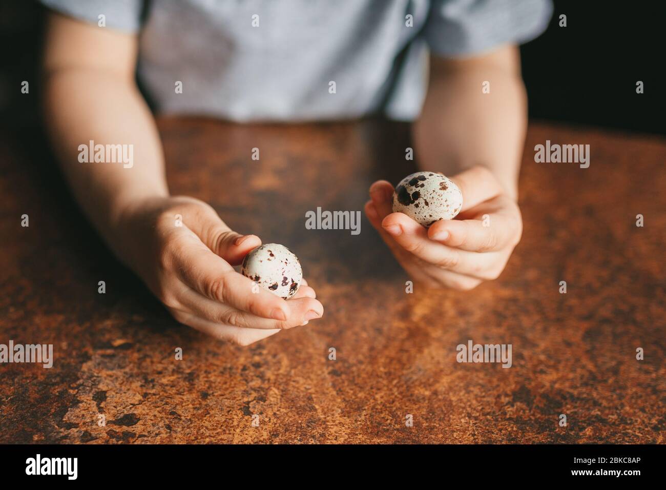 Cropped frame of a child sitting at the table and preparing to eat quail eggs. Diet food, breakfast. Proper nutrition. Healthy lifestyle. Selective fo Stock Photo