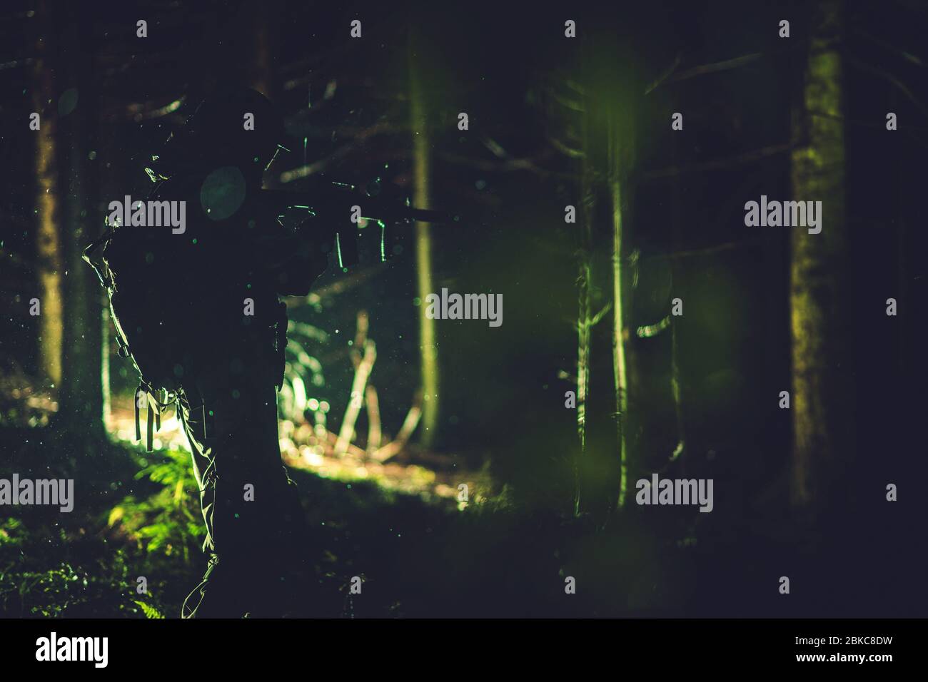 Soldier with Assault Rifle in Action in Dark Rainy Forest. Army and Military Theme. Stock Photo