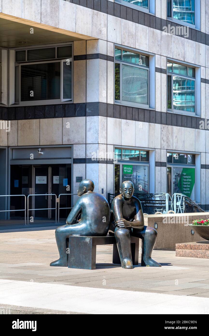 'Two Men on a Bench' bronze sculpture by Giles Penny in Canary Wharf, London, UK Stock Photo