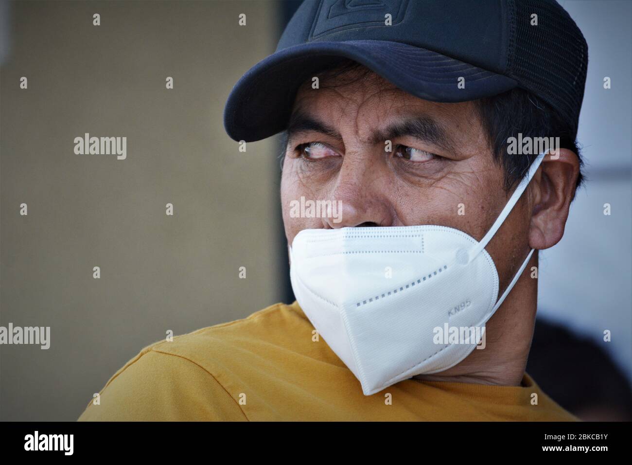 Hispanic middle aged man wearing face mask for covid 19 the wrong way, by not covering his nose in public at a bank in Los Angeles California USA Stock Photo