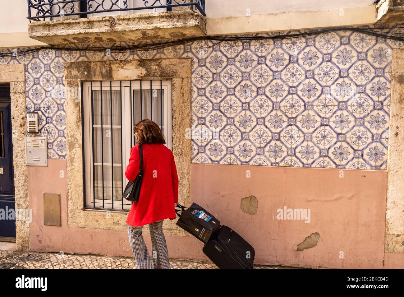 Lisbon, Portugal - 8 March 2020: Tourist with luggage walking in front of traditional portuguese decorative tiles azulejos Stock Photo