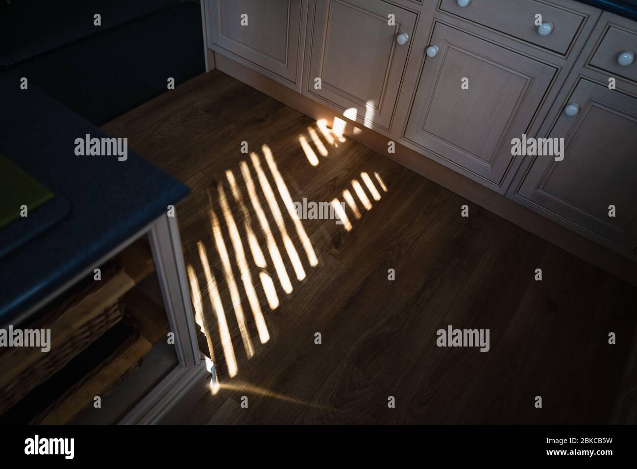 Golden light strips across a kitchen floor created by light shining