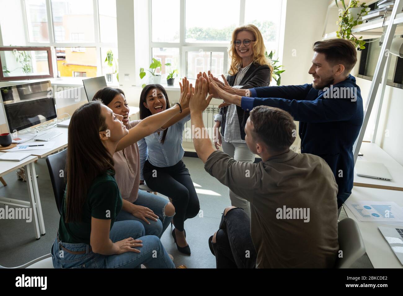 Multiracial employees team with male leader, coach giving high five ...