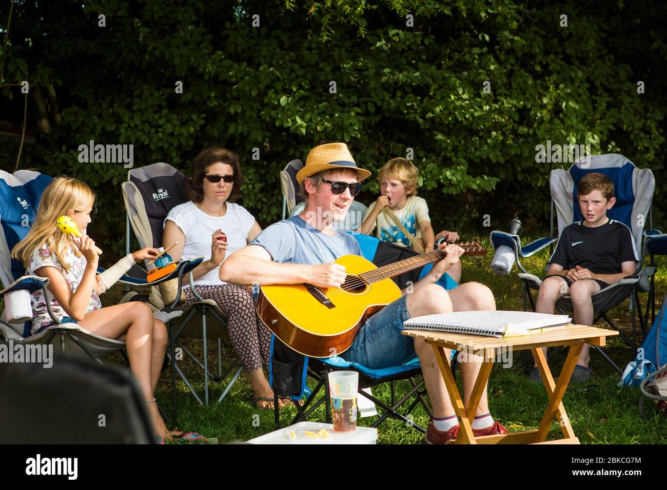 Family singing songs with acoustic guitar on a summer camping holiday at Wowo's, a family campsite in Sussex Stock Photo