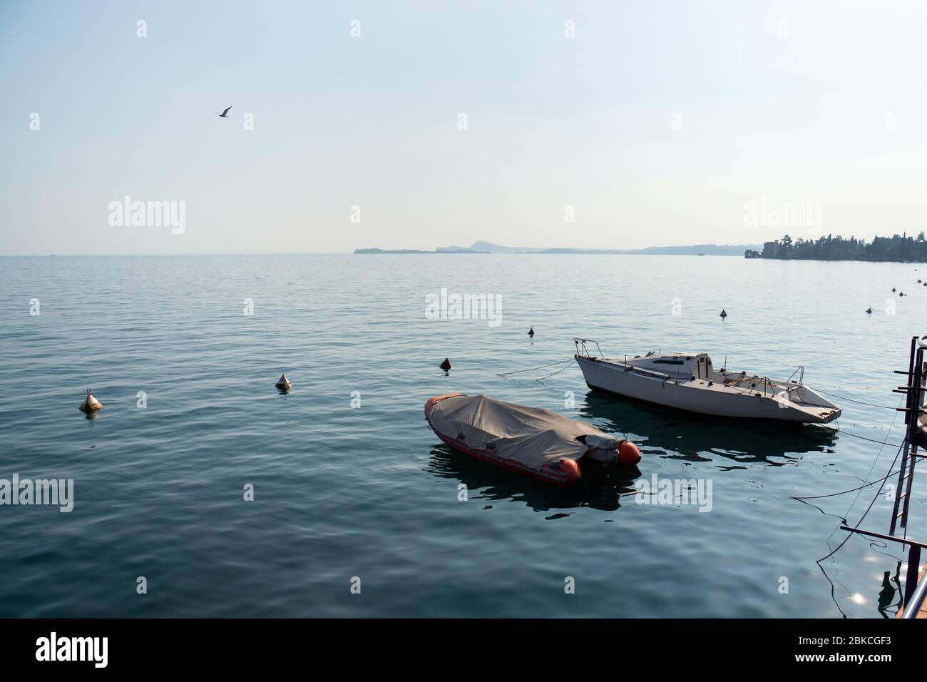 Two boats and silent water surface. Warm September day at lake Garda, northern Italy. Stock Photo