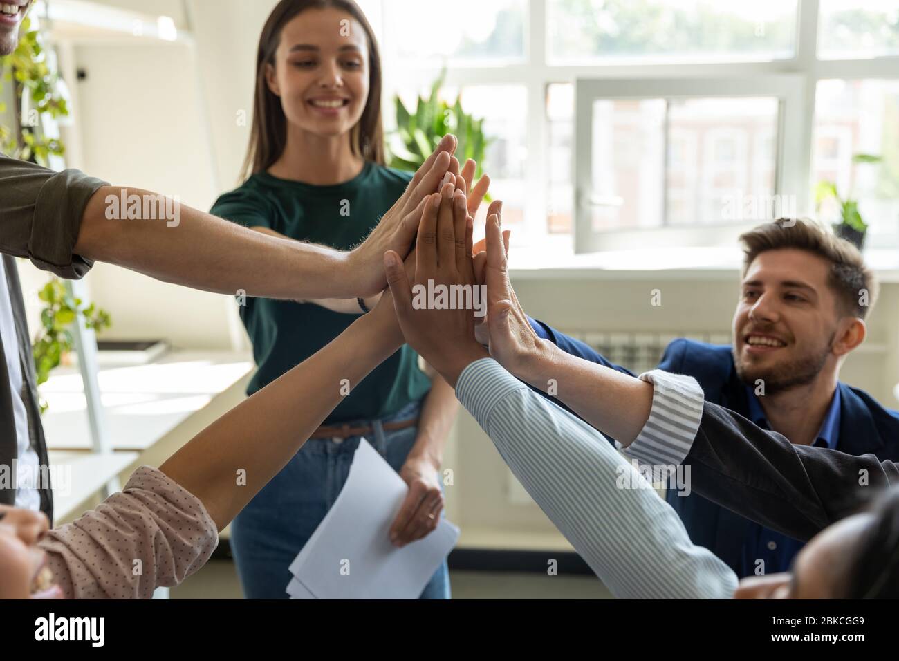Diverse workers with happy female leader, coach giving high five Stock ...