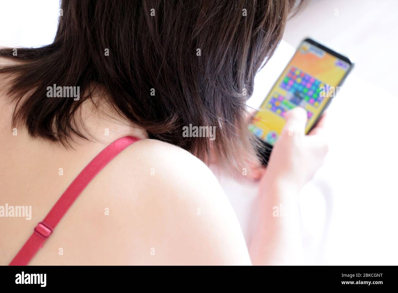 Girl playing casual game on smartphone. Mobile phone in female hand, concept of social media, gaming addiction Stock Photo