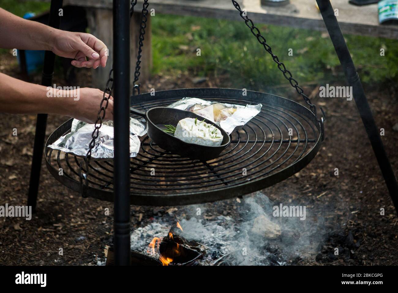 Cooking food over a campfire on a hanging barbecue at Wowo's, a family campsite in Sussex Stock Photo