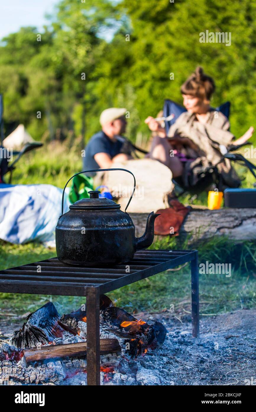 Boiling a huge blackened kettle for a cup of tea an open fire whilst camping in Kent, UK Stock Photo