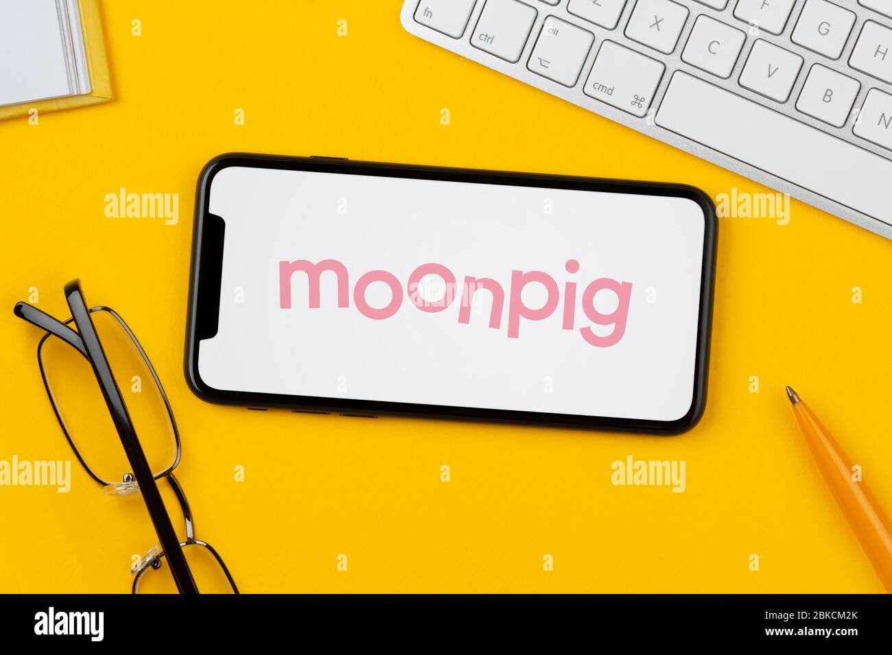 A smartphone showing the Moonpig logo rests on a yellow background