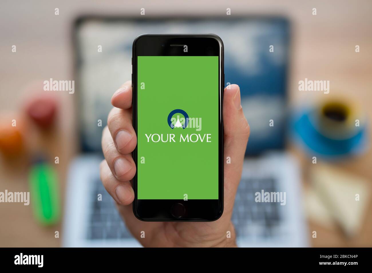 A man looks at his iPhone which displays the Your Move logo (Editorial use only). Stock Photo