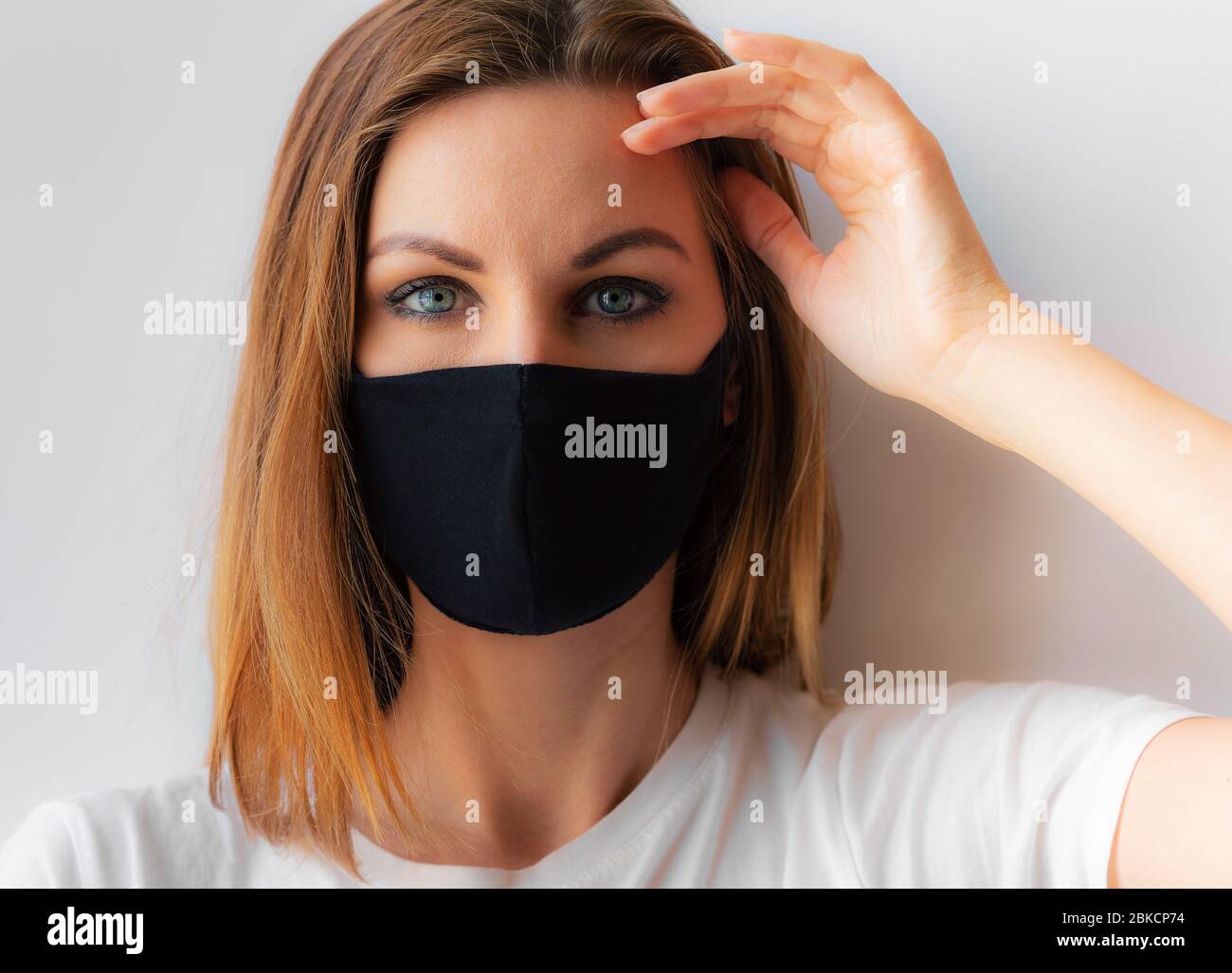 Beautiful portrait of a young woman in a black medical mask and blue ...