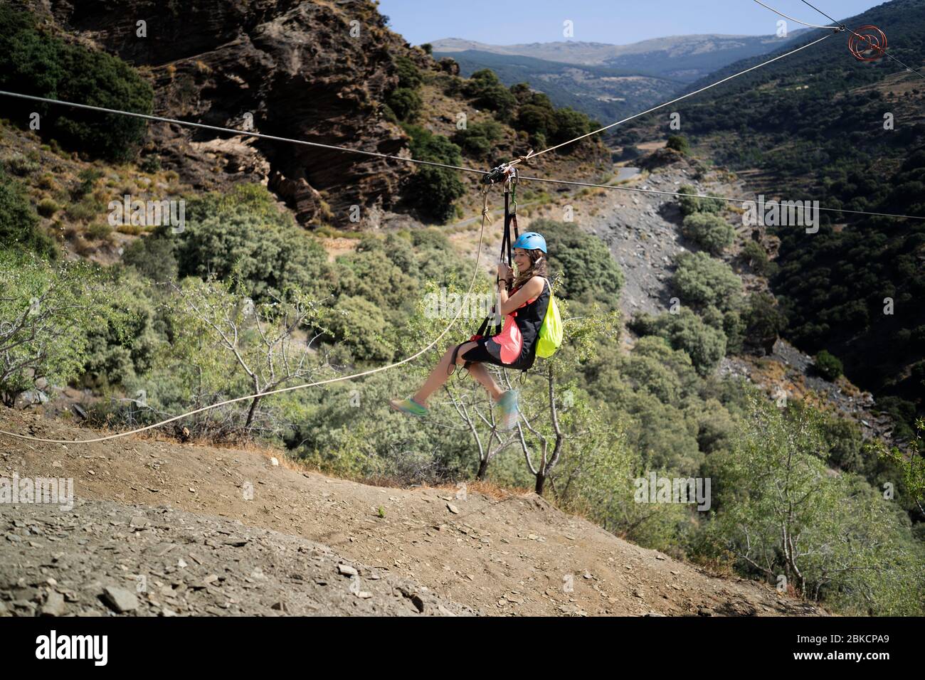Woman hanging on a rope-way. Zip line is an exciting adventure activity. Tourists ride on the Zip line through the mountain. Stock Photo