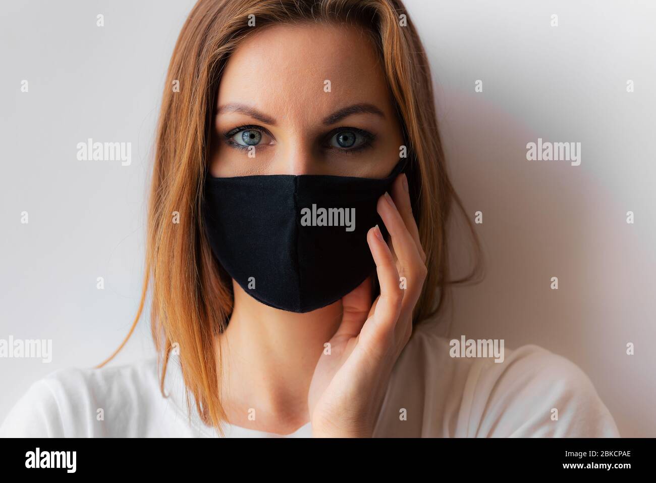 Beautiful portrait of a young woman in a black medical mask and blue ...