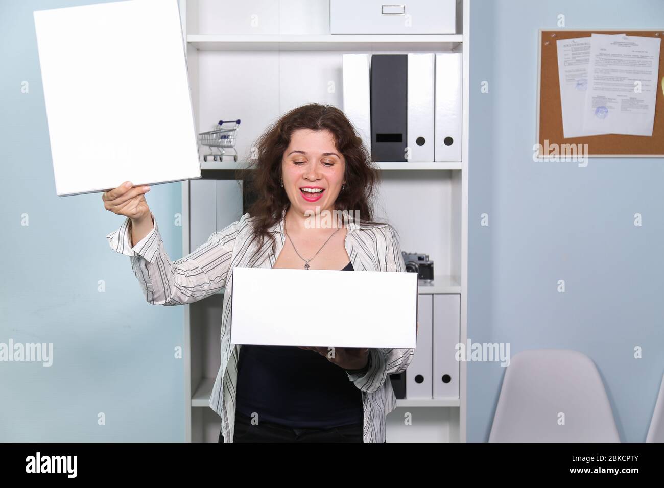 Concept of dismissal from work. Happy woman with carton box with her stationery stuff, girl was fired from her job. Stock Photo