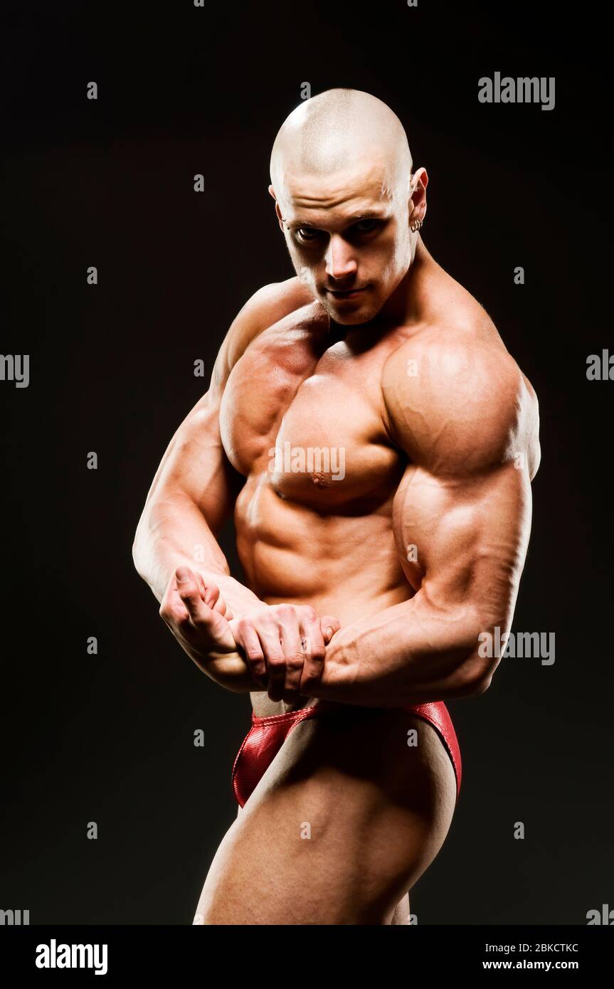Body Builder Posing - Side Chest. Strong healthy power fitness handsome  athletic man with muscular trained body flexing his chest and biceps on  black Stock Photo - Alamy