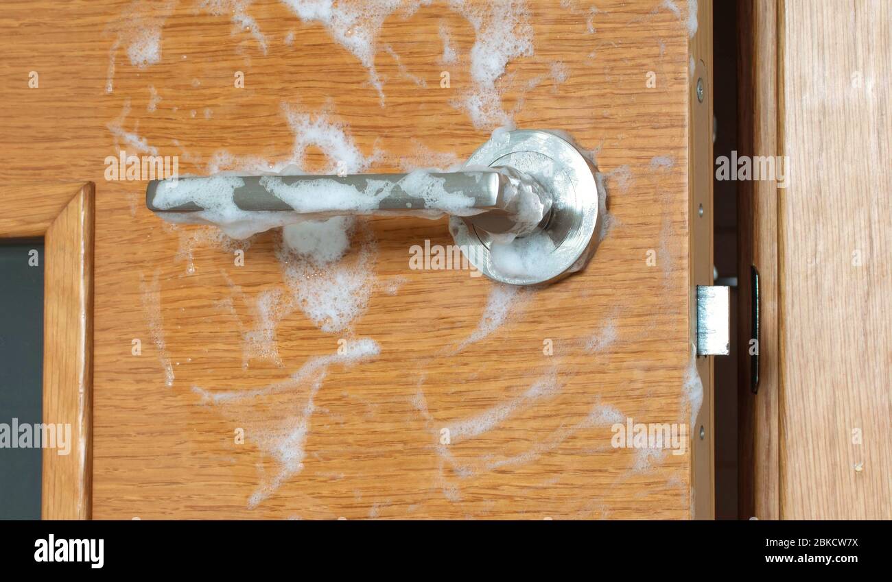 Door handle covered with soap foam. Home cleaning and desinfection during virus outbreak. Stock Photo