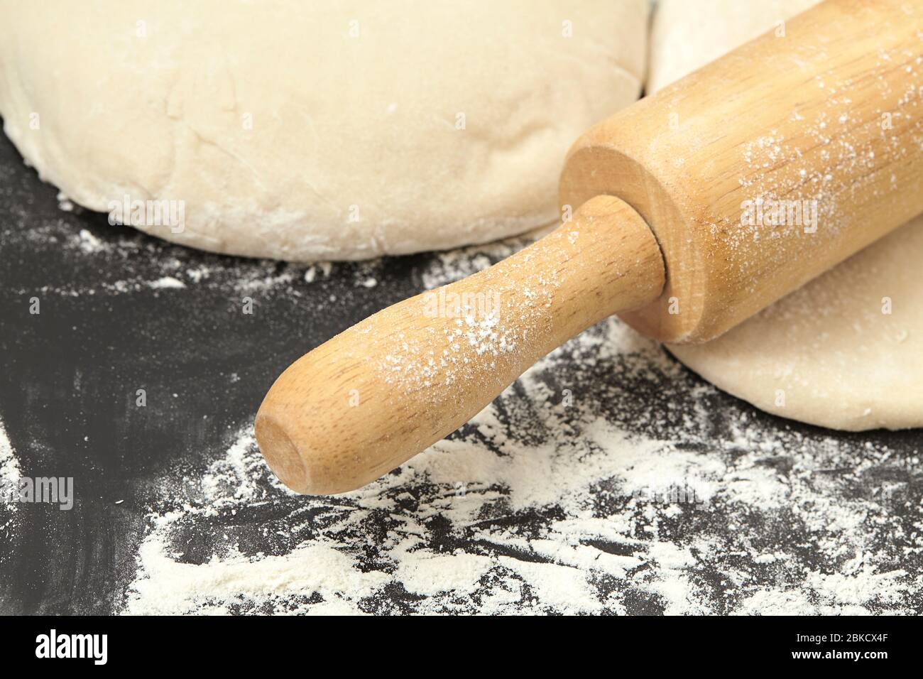 Dough and wood rolling pin on clean black background Close up Stock