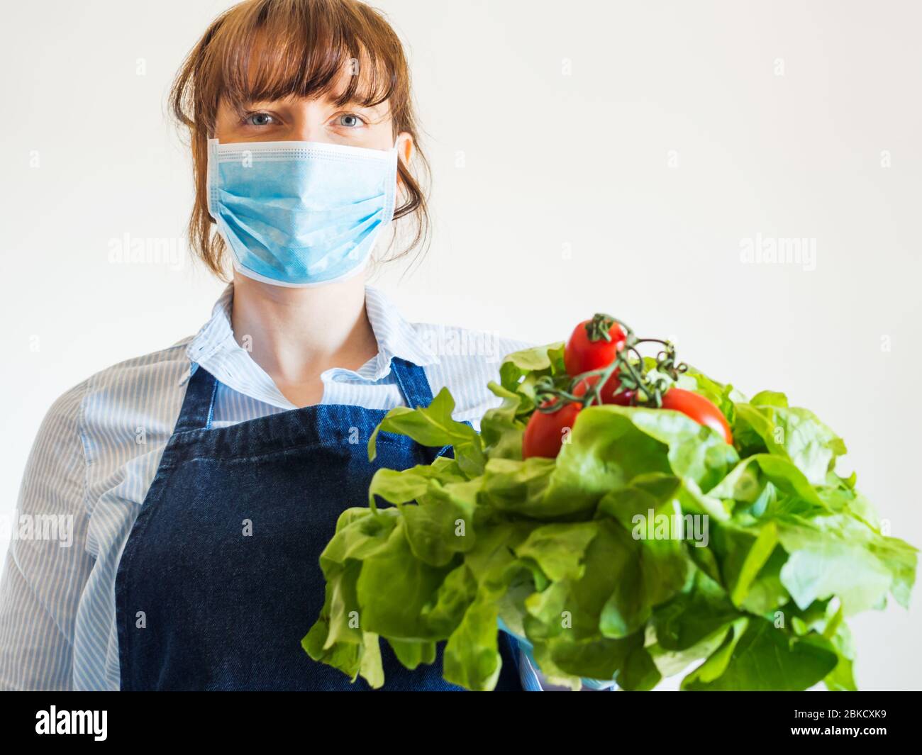 Woman in blue in face mask with fresh produce Stock Photo - Alamy