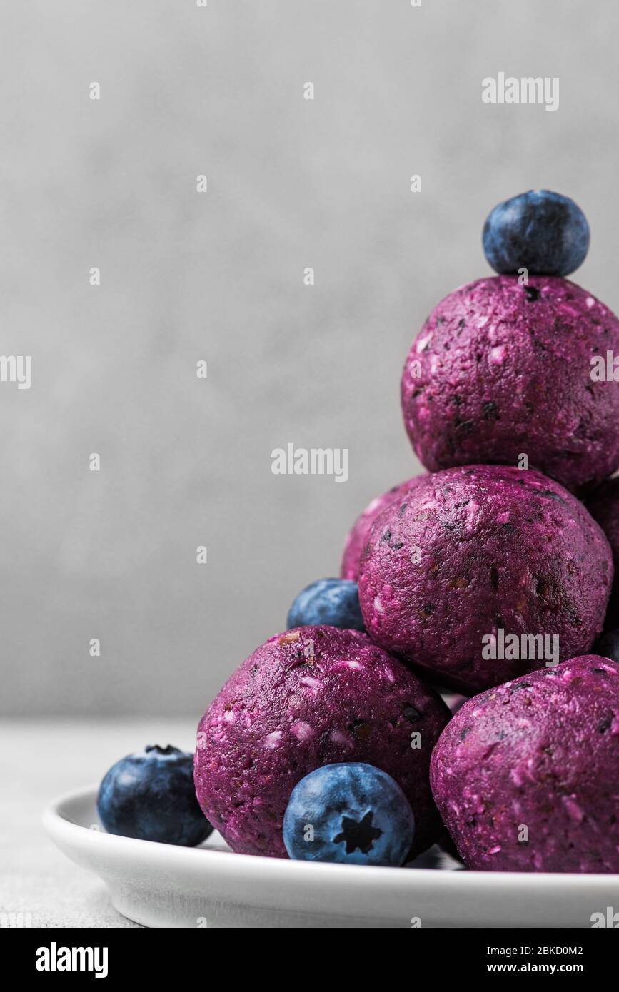 Raw energy balls with blueberries and acai powder. Healthy vegan food dessert. vertical orientation. close up Stock Photo