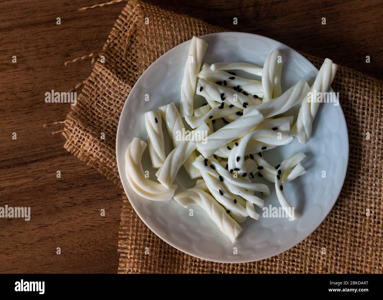 White braided cheese with black sesame served in a white plate Stock Photo