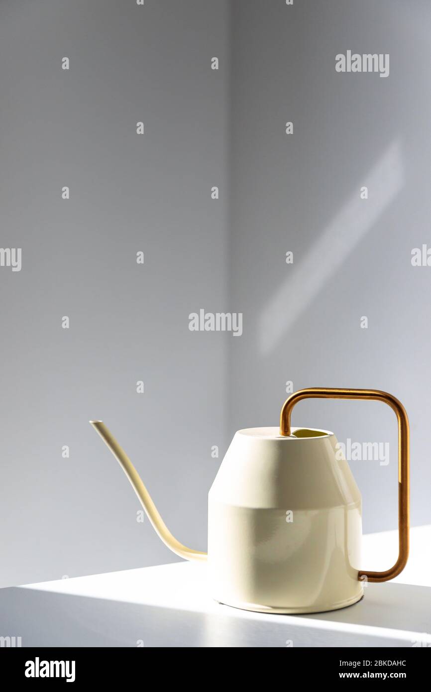 Close up of elegant white metallic watering can with long thin spout and yellow thin circular